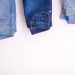 Three pairs of denim jeans neatly folded and hanging against a white backdrop.