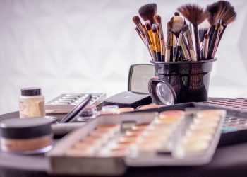 Close-up of a professional makeup brush set and cosmetics on a table for beauty use.