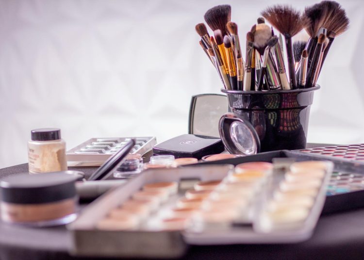 Close-up of a professional makeup brush set and cosmetics on a table for beauty use.