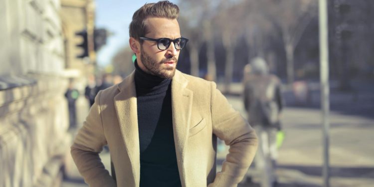 Stylish man in glasses and coat posing outdoors on an urban street in Budapest.