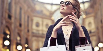 Elegant woman wearing sunglasses shopping in Milan's iconic Galleria Vittorio Emanuele II.